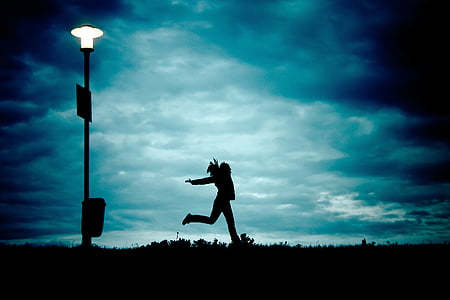 silhouette of woman running near lighted post thumbnail