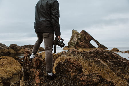 man standing while holding DSLR camera near sea at daytime thumbnail