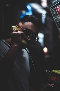 man using coin operated telephone at nighttime thumbnail