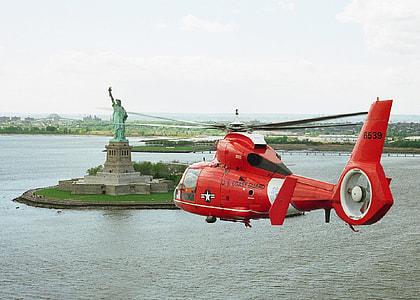 red helicopter flying towards Statue of Liberty thumbnail