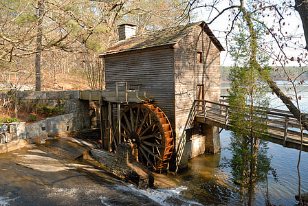 brown wooden watermill with wooden bridge under tree during daytime thumbnail