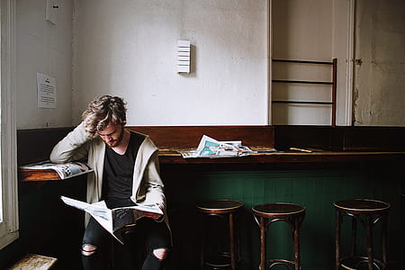 man leaning on desk while reading newspaper thumbnail