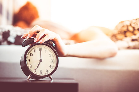 Woman Shutting Off Ringing Alarm Clock From Bed thumbnail