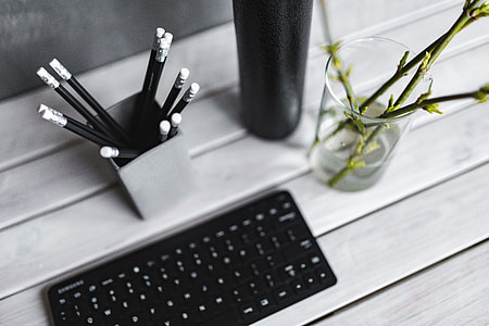 Black keyboard with pencils on a white table thumbnail