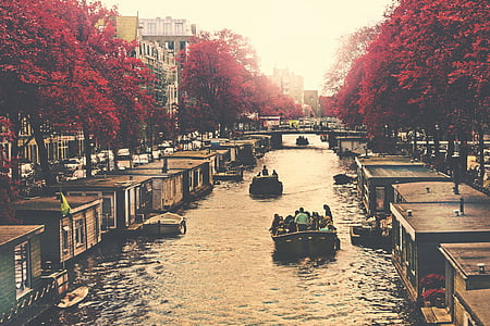 several boats full of people in the middle of canal on a urban city during day thumbnail
