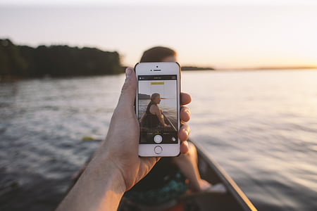 person holding silver iPhone 6 and taking selfie thumbnail