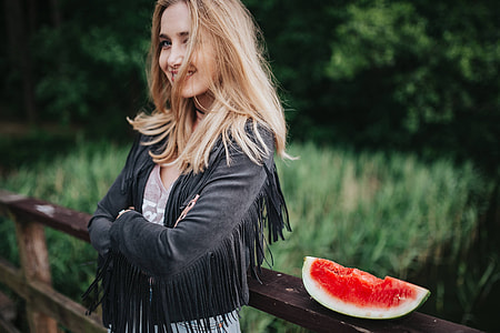 Blonde woman having a healthy snack at the wooden pier thumbnail