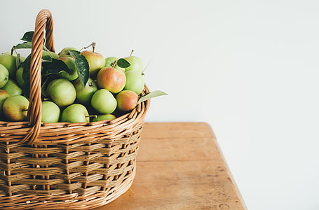 brown wicker basket filled with apples on brown wooden desk thumbnail