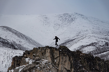 man on top of brown mountain near white mountains during daytime thumbnail