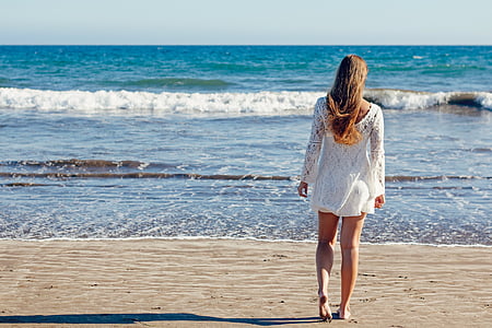 woman walking towards beach shore thumbnail