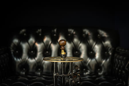 selective focus photography of steampunk lamp near tufted black sofa thumbnail