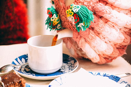 person pouring tea on white ceramic cup on table thumbnail