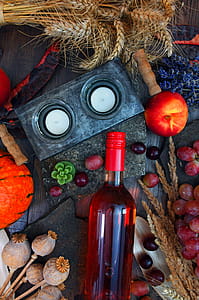 Gray Candle Holder Near Glass Bottle and Round Red Fruit on Gray Wooden Surface thumbnail