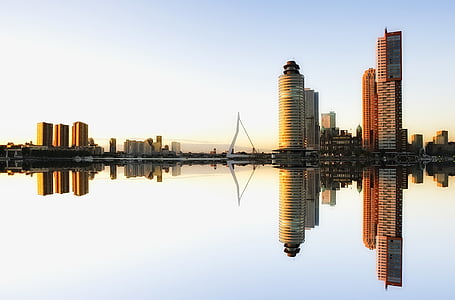 high rise concrete building near grey calm body of water under blue sky at daytime thumbnail