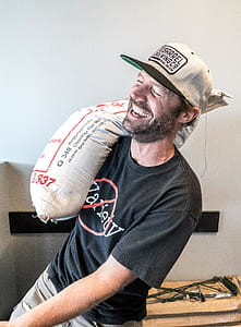 Man Carrying Sack Near White Wall thumbnail