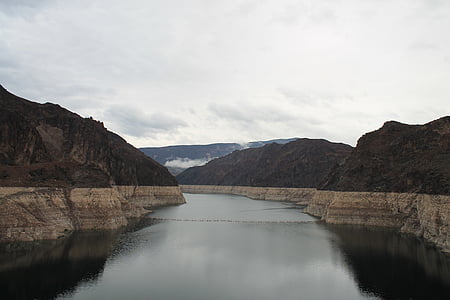 body of water between mountains under cloudy sky thumbnail