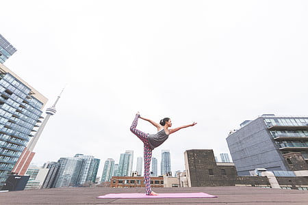 woman doing yoga on yoga mat on top of building during daytime thumbnail