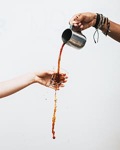 person pouring beverage on clear rocks glass held by another person thumbnail