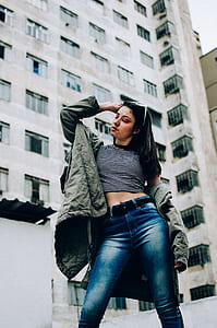 woman in striped shirt wearing sunglasses posing near high-rise building thumbnail