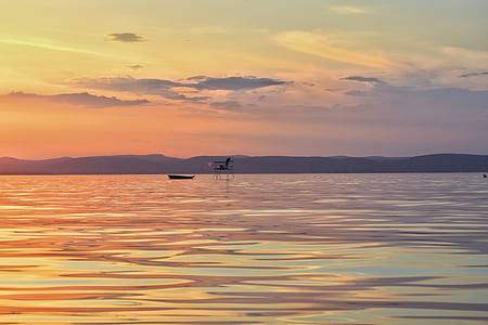 silhouette of boat on water at golden hour thumbnail