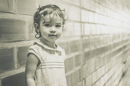 grayscale photo of girl standing behind wall thumbnail
