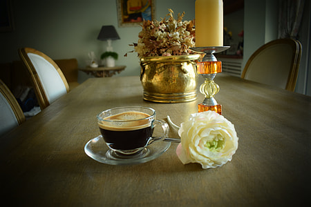 coffee in glass cup beside white rose and candle holder on dining table thumbnail