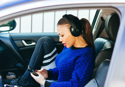 woman sitting on bucket seat while using her headphones thumbnail