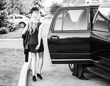 grayscale photo of woman standing beside car thumbnail