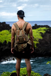 man standing on cliff carrying backpack thumbnail