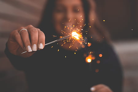 shallow focus photography of woman holding orange sparkle thumbnail