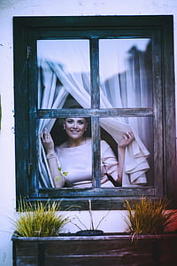 smiling woman opening the curtain at the window pane thumbnail