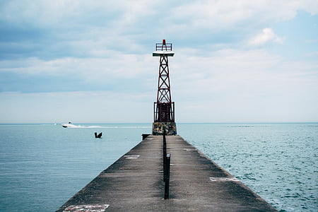 gray concrete dock beside sea and transmission post thumbnail