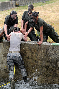 woman in type-B army uniform being pulled-up over water by three women thumbnail