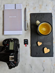 black DSLR camera near black SanDisk memory card and gray Whatever book thumbnail