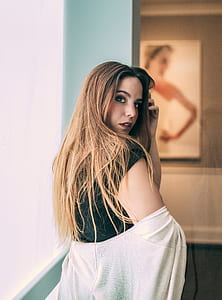 woman standing near painting holding hair leaning sideways thumbnail