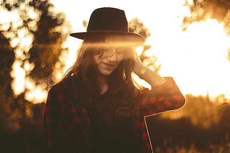 woman wearing red and black checkered dress shirt and black hat during sunrise thumbnail