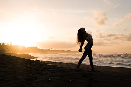 woman stretching her body at beach side during golden hour thumbnail