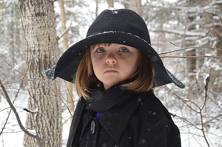 girl wearing black cap on snowfield forest thumbnail