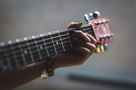 selective focus photo of person playing brown guitar thumbnail