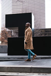 man walking on gray pathway near the black wall at daytime thumbnail