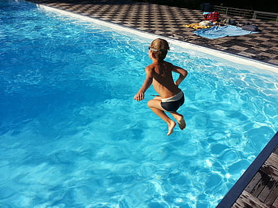 boy jumping on swimming pool during daytime thumbnail