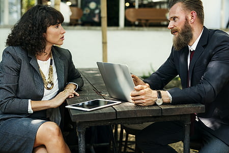 man and woman having conversation both leaning on black wooden table thumbnail