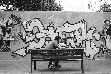man and woman kissing while sitting on brown bench thumbnail