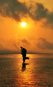 fishermen walking on beach shore during golden hour thumbnail