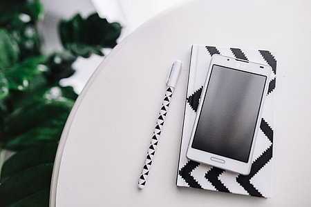 Black-and-white notebook and a white smartphone with various items thumbnail
