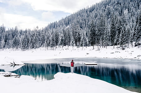 woman standing on snow near body of water thumbnail
