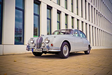 classic gray sedan parked beside white concrete building at daytime thumbnail