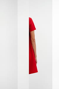 woman wearing red dress hiding on white wall thumbnail