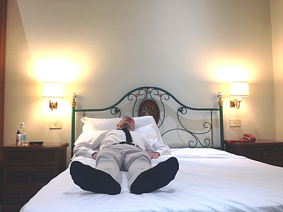 man in suit lying on white bed thumbnail