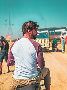 man wearing white and maroon raglan shirt sitting down on motorcycle thumbnail